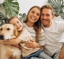 Happy mother, father, cute, little daughter hugging together with dog, golden retriever