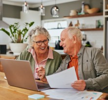 Happy old couple managing home finances on laptop